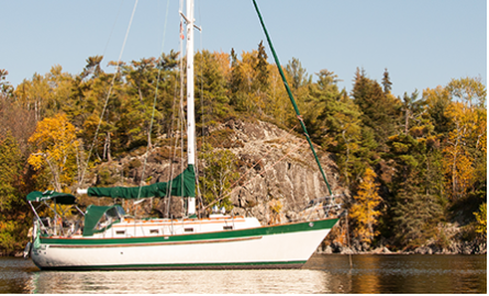 white and green sail boat with its sail down 